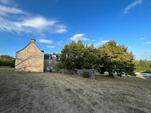 un antiguo edificio de piedra en un campo con árboles en Le Mas de Coursac en Quissac