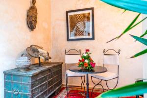 Pokój ze stołem i 2 krzesłami z kwiatami w obiekcie Riad Boustane w Marakeszu