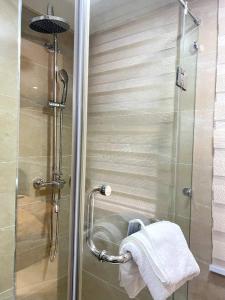 een douche met een glazen deur en een handdoek bij Iconic Towers Blue Room in Igboshere