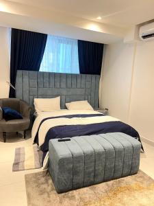een slaapkamer met een groot bed en een stoel bij Iconic Towers Blue Room in Igboshere