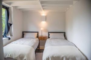 two beds in a room with white walls at Well Barn Sudbourne in Sudbourne