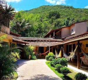 a house with a hammock hanging outside of it at Pousada Refúgio Do Capitão in Praia de Araçatiba
