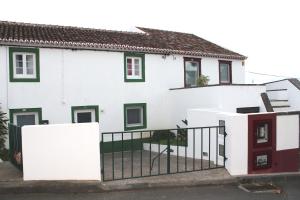 una casa blanca con adornos verdes y una valla en Casa do Largo, en Lagoa