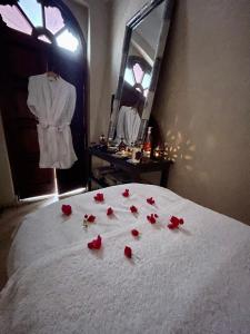 a pile of red roses on a bed with a mirror at Riad Elias & Spa in Marrakesh