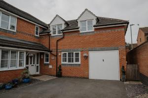 a brick house with a white garage at Lovely new 1 bedroom loft apartment with on drive parking in Trowbridge