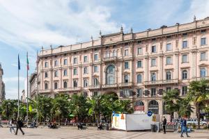 a large beige building with palm trees in front of it at easyhomes Duomo View in Milan