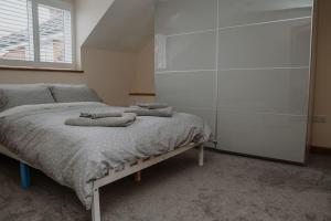 a bedroom with a bed with towels on it at Lovely new 1 bedroom loft apartment with on drive parking in Trowbridge