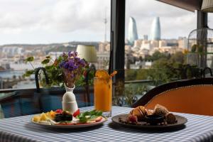una mesa con dos platos de comida y zumo de naranja en Sapphire City Hotel en Baku