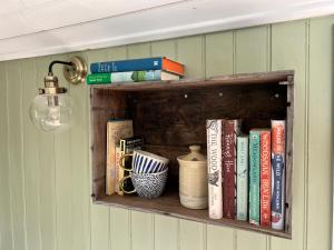 un estante de libros con libros y tazas. en Stonehenge Campsite & Glamping, en Berwick Saint James