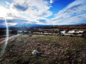 an open field with a river and mountains in the background at Cabañas Ladera de Nant y Fall -Tiny Houses- in Trevelín