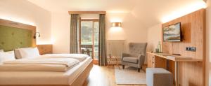 a hotel room with a bed and a chair at Hotel Nagglerhof am Weissensee in Weissensee