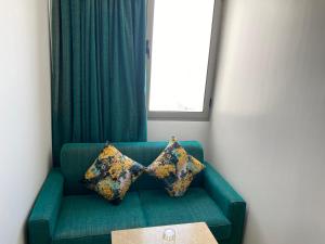 Hotel Azur في الدار البيضاء: أريكة خضراء مع وسادتين عليها نافذة