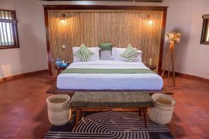 a bedroom with a large bed with a wooden headboard at Tilenga Safari Lodge in Arua