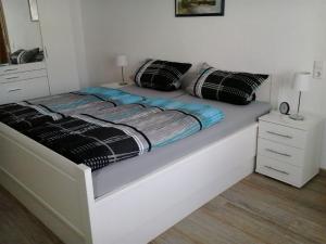 a white bed with black and blue sheets and pillows at Ferienwohnung Hunold in Marsberg