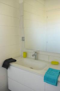 La salle de bains blanche est pourvue d'un lavabo et d'un miroir. dans l'établissement Maison Piscine personnelle vue mer COSY, au Marin
