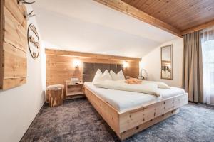1 dormitorio con 1 cama grande y pared de madera en Ferienwohnungen Fichtenheim, en Mayrhofen