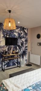 een slaapkamer met een muur met een muurschildering van palmbomen bij Au Nid des Champs, Agréable chambre d'hôtes avec jacuzzi sur demande, proche de Chartres in Chartres