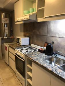 cocina con fogones horno de arriba junto a un fregadero en Departamento - Edificio Costanera en San Salvador de Jujuy