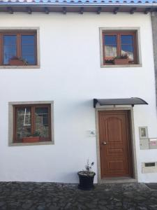 a white building with a brown door and three windows at Casa do Castelo II in Bragança