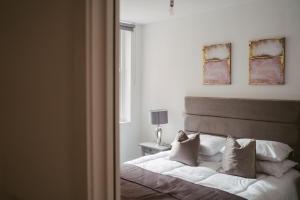 una camera da letto con letto, lenzuola e cuscini bianchi di Apartment 4 2 bedroom, sleeps x 6 a York