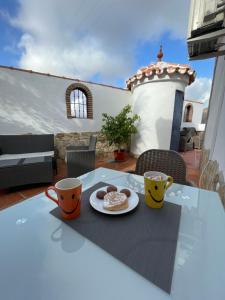 una mesa con dos tazas y un plato de comida en ella en B&B Casa El Viaje en Cómpeta