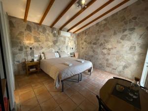 1 dormitorio con cama y pared de piedra en B&B Casa El Viaje, en Cómpeta
