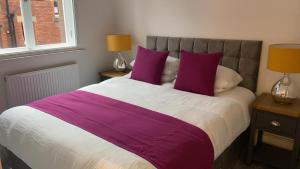 a bed with purple and white sheets and two lamps at Apartment 5 4 bedrooms, sleeps x 15 in York