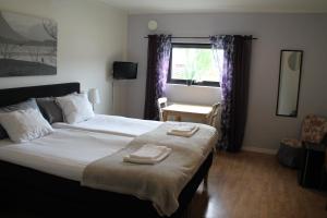 a bedroom with a large bed with two towels on it at Rödlix Vandrarhem & Camping in Tvååker