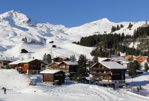 a ski resort with snow covered buildings on a mountain at Pension Mezzaprada in Arosa