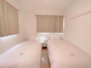 duas camas num pequeno quarto com lençóis brancos em ヴィラ山間堂GrandVilla Mt Fuji view BBQ Bonfire AnnoVillas Sankando em Fujikawaguchiko