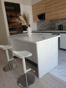 a kitchen with a white counter and two stools at Lovely 1-bedroom rental unit in downtown in Dushanbe