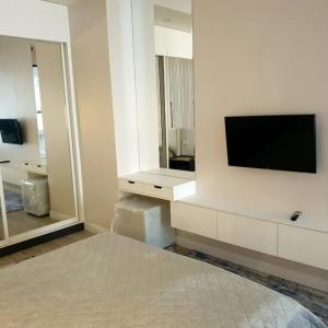 a white room with a tv and a bed and mirror at Lovely 1-bedroom rental unit in downtown in Dushanbe