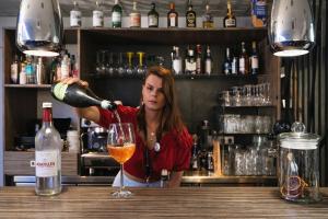 una mujer sirviendo una copa de vino en un bar en Urban Style LES FLEURINES, en Villefranche-de-Rouergue