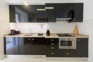a kitchen with black cabinets and a sink at Otília Apartamentos in Lisbon