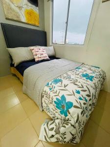 a bedroom with a bed with a flower patterned comforter at Lovely 2 bedroom condo unit in Iloilo City