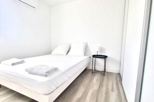 biała sypialnia z łóżkiem i lustrem w obiekcie Résidence Anthérieu - Appartements neufs tout confort w mieście Frontignan