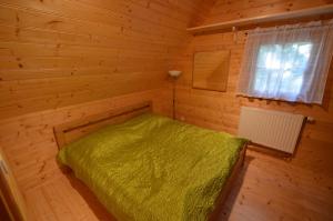 - une chambre en bois avec un lit vert dans l'établissement Meadow Ranch Holiday Home, à Jaroslavické Paseky