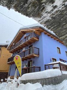 una casa azul con una tabla de snowboard delante de ella en Rifugio Lilla, en La Thuile