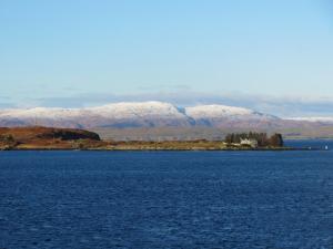 a large body of water with snow covered mountains in the background at Three Oban in Oban