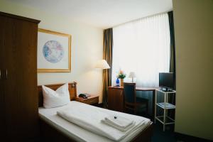 a hotel room with a bed and a desk and a window at Altstadt Hotel St. Georg in Düsseldorf