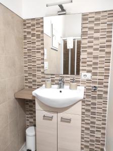 ein Badezimmer mit einem weißen Waschbecken und einem Spiegel in der Unterkunft Dove nasce il Sole B&B in Nicolosi
