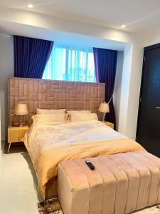 a bedroom with a large bed with blue curtains at Iconic Tower Pink Room in Lagos