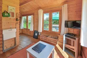 Cabaña de madera con sala de estar con mesa y TV. en The Cabin with Hot Tub en Maidstone