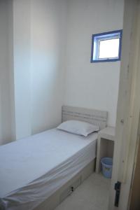 1 dormitorio con 1 cama blanca y ventana en Penginapan AIRA, en Palu