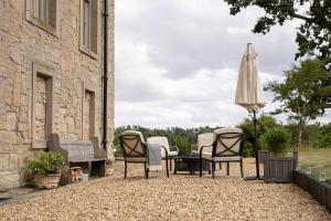 a patio with a table and chairs and an umbrella at Blanerne House in Duns