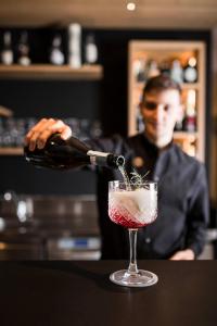 Ein Mann schüttet eine Flasche Wein in einen Cocktail ein in der Unterkunft Alpinhotel Vajolet - Adults only in Tiers