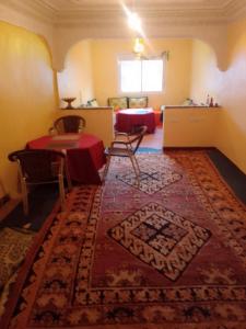 Cette chambre dispose d'une table et d'un tapis. dans l'établissement Maison D'hote Amazir, à Boumalne