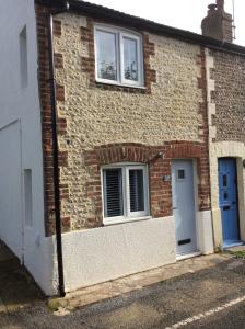 a brick house with two windows and a blue door at Tremeer Cottage in Upper Beeding