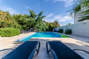 a swimming pool with two benches next to a building at Apartments Milivoj in Seget Vranjica