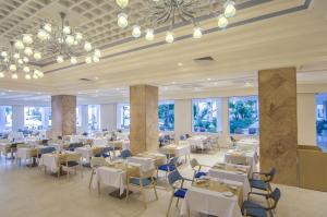 un restaurant avec des tables blanches, des chaises et des fenêtres dans l'établissement Royal Azur Thalassa, à Hammamet